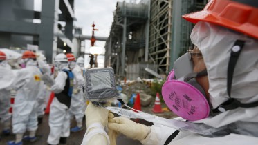 09 Jul 2014, Japan --- epa04307505 A Tokyo Electric Power Co.'s staff measures radiation dose as workers construct an ice wall to freeze highly toxic water at tsunami-crippled Tokyo Electric Power Co.'s Fukushima Daiichi Nuclear Power Plant in Okuma, Fukushima Prefecture, northeast of Tokyo, Japan, 09 July 2014. Tokyo Electric Power Co.(TEPCO) conducts to build frozen ice wall around the buildings of Units 1 to 4 at the tsunami-devastated nuclear power plant to stop radiation-contaminated water from flowing to the sea. TEPCO has been struggling with massive amounts of toxic water as the operator continues to pump water into three reactors to keep them cool. The plant suffered meltdowns at three of its six reactors after a tsunami swept through the facilities in March 2011. EPA/KIMIMASA MAYAMA/POOL --- Image by © KIMIMASA MAYAMA/POOL/epa/Corbis